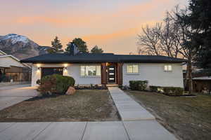 View of front of home featuring brick siding, a chimney, a garage, driveway, and a mountain view