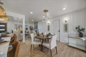 Dining space with light wood-style flooring, recessed lighting, and a decorative wall