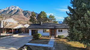 Ranch-style home featuring a mountain view, concrete driveway, an attached garage, a chimney, and brick siding