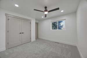 Unfurnished bedroom featuring light carpet, a closet, ceiling fan, and recessed lighting