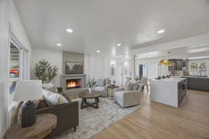 Living room featuring light wood-type flooring, recessed lighting, and a warm lit fireplace