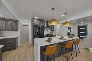 Kitchen featuring a kitchen breakfast bar, light stone counters, light wood-style floors, a kitchen island, and tasteful backsplash
