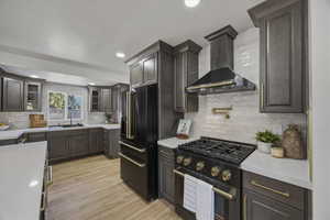 Kitchen with black appliances, tasteful backsplash, recessed lighting, light wood-style flooring, and light stone countertops
