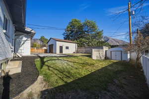 Fenced backyard featuring a patio area, a garage, a mountain view, and a storage unit