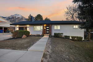View of front facade with brick siding, a chimney, an attached garage, and a yard