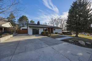 Ranch-style house with concrete driveway, a chimney, an attached garage, and brick siding
