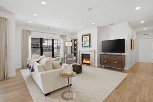Living area featuring light wood-type flooring, a glass covered fireplace, and recessed lighting