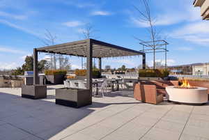 View of patio / terrace featuring an outdoor fire pit, an outdoor lounge area with bar, a pergola, and exterior kitchen