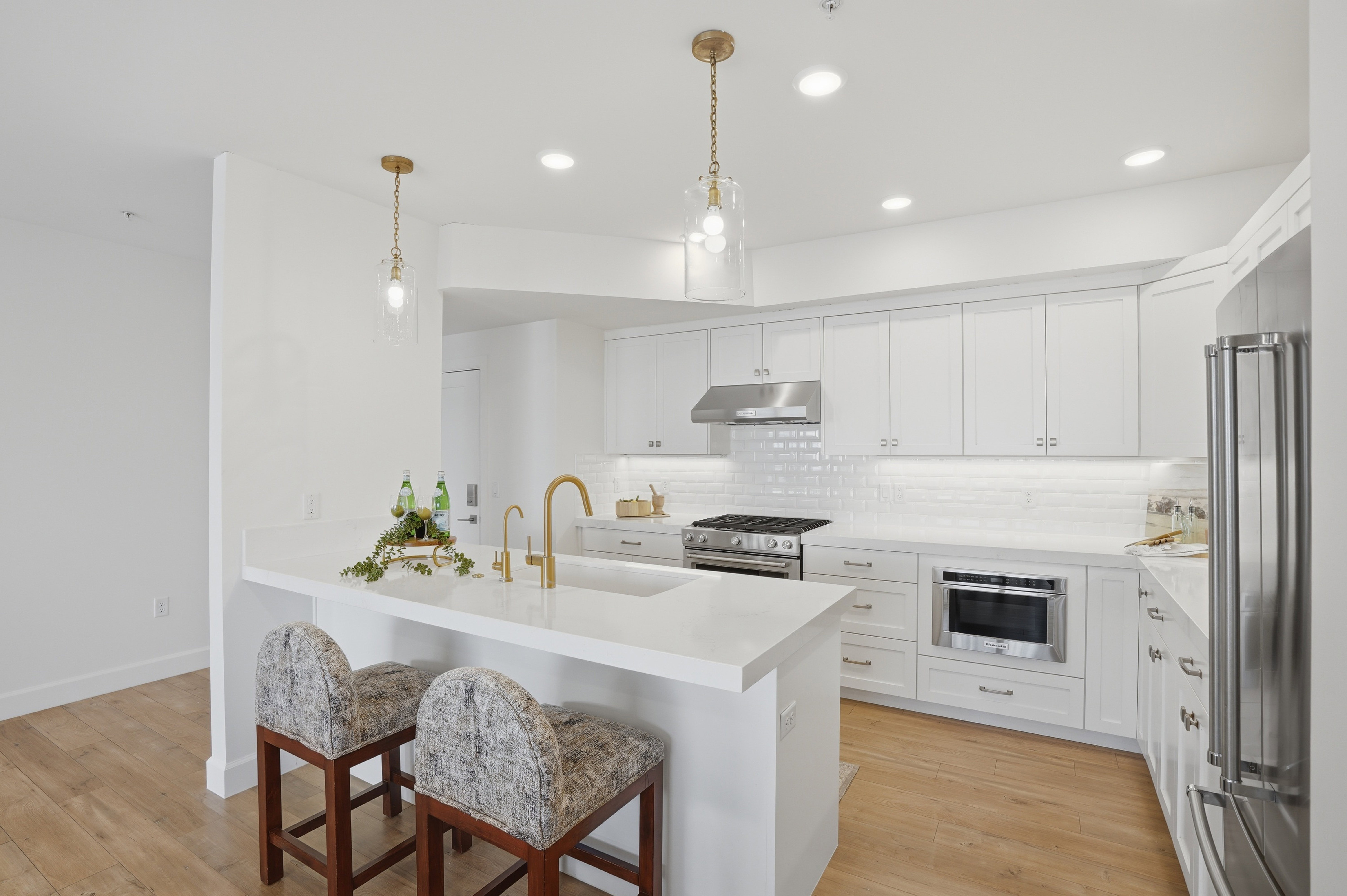 Kitchen featuring a breakfast bar area, white cabinets, high end appliances, and light wood-style flooring