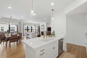 Kitchen with decorative light fixtures, white cabinetry, light wood-style flooring, and a glass covered fireplace