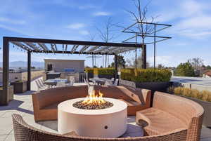 View of patio featuring an outdoor kitchen, a pergola, an outdoor fire pit, and a mountain view