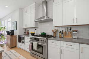 Kitchen featuring stainless steel appliances, white cabinetry, light wood-style flooring, recessed lighting, and decorative backsplash