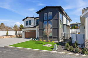 Modern home with an attached garage, driveway, and a gate