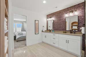 Ensuite bathroom with double vanity, recessed lighting, and light wood-style floors