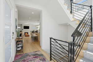 Staircase with wood-type flooring, a lit fireplace, and recessed lighting