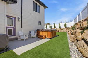Fenced backyard featuring a hot tub and a patio