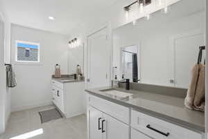Bathroom with two vanities, curtained shower, light tile patterned floors, and recessed lighting