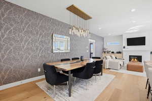 Dining room with light wood-style flooring, a fireplace, recessed lighting, and wallpapered walls