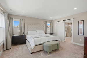 Primary Bedroom featuring a barn door, light carpet, and recessed lighting