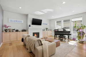 Living area featuring light wood-type flooring, plenty of natural light, a fireplace, and recessed lighting