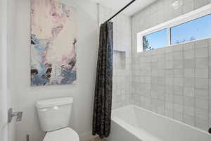 Bathroom with toilet and shower / bathtub combination with curtain