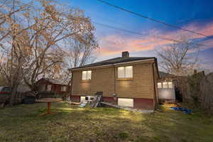 Rear view of house featuring a lawn and brick siding