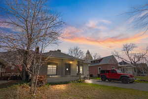 View of front of house with brick siding, a yard, a chimney, and a porch