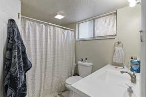 Bathroom with a textured ceiling, a shower with curtain, and vanity