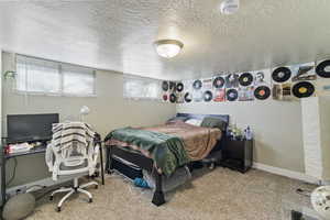 Bedroom with a textured ceiling, light carpet, and an office area