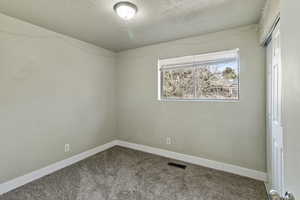 Carpeted empty room featuring baseboards and a textured ceiling
