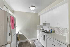 Kitchen featuring white appliances, white cabinets, light countertops, dark wood-type flooring, and a textured ceiling