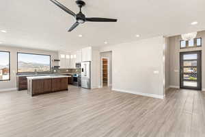 Kitchen with open floor plan, stainless steel appliances, a center island, light countertops, and open shelves
