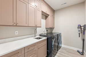 Laundry area with light wood-style flooring, cabinet space, and washer and dryer