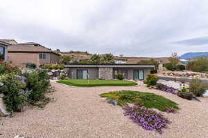 Back of house featuring a putting area, a mountain view, and stucco siding