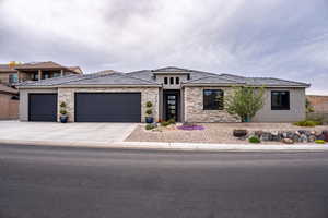 Prairie-style home with stucco siding, a garage, driveway, and stone siding