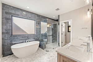 Full bathroom featuring a shower stall, double vanity, a freestanding bath, plenty of natural light, and recessed lighting