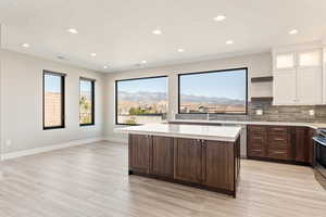 Kitchen featuring open shelves, tasteful backsplash, dark wood finish cabinets, glass insert cabinets, and a kitchen island