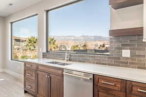 Kitchen with backsplash, stainless steel dishwasher, light stone counters, and a mountain view