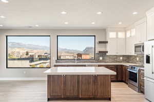 Kitchen featuring open shelves, stainless steel appliances, light wood finished floors, a kitchen island, and recessed lighting