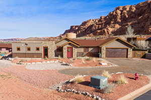 View of front of property featuring stone siding, a mountain view, stucco siding, and a garage