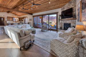Living room with a high wooden beamed ceiling, a fireplace, ceiling fan, and sliding doors
