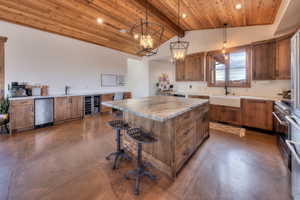 Kitchen featuring Knotty Alder cabinetry, massive center island, wine cooler, concrete flooring, and a breakfast bar