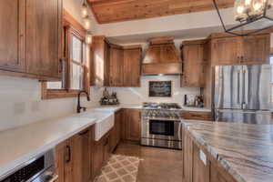 Kitchen featuring stainless steel appliances, Knotty Alder cabinetry, Apron sink, wood ceiling, and light Quartz counters