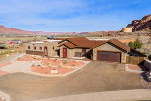 View of front of house with stone siding, driveway, a garage, and a mountain view