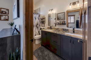 Bathroom with double vanity, polished granite countertop and tiled bath/shower