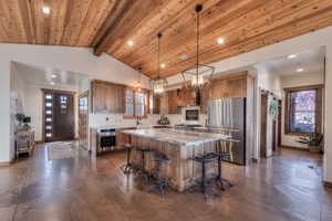 Kitchen featuring stainless steel appliances, Leathered Quartzite Countertops, Knotty Alder Cabinets and finished concrete floors