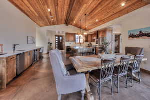 Dining area with finished concrete floors, wet bar with beverage cooler and sink, office area and a high wooden beamed ceiling