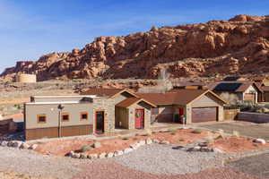 View of front of house with stone siding, a mountain view, driveway, and an attached garage