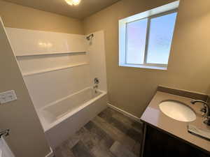 Basements Full bathroom with vanity, dark wood-style flooring, and shower / bath combination