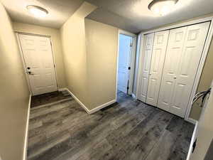 Corridor featuring a textured ceiling and dark wood finished floors bathroom entrance and rear basement walkout